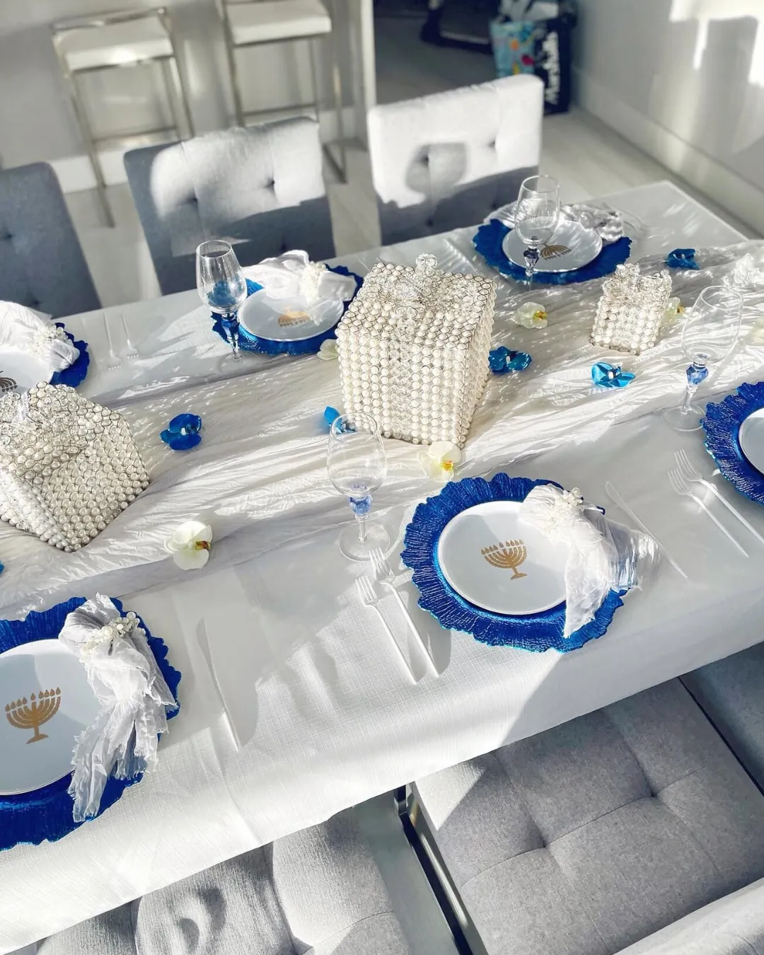 Overhead view of a Hanukkah dinner table set with menorah plates and blue chargers