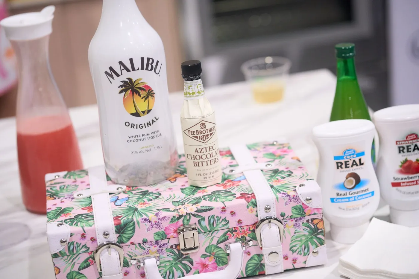 Malibu rum and Fee Brothers chocolate bitters bottles on a floral cocktail case