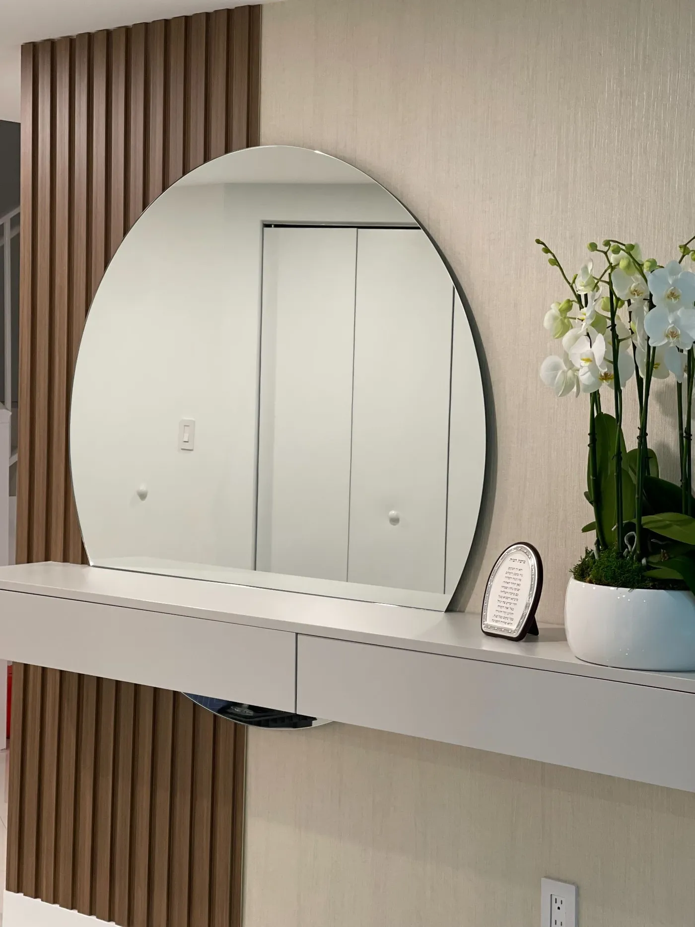 Arched wall mirror above a console table with orchids and a decorative frame