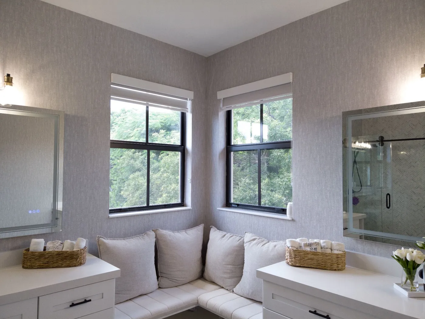 Corner window seat with cushions between two large windows in a bathroom nook
