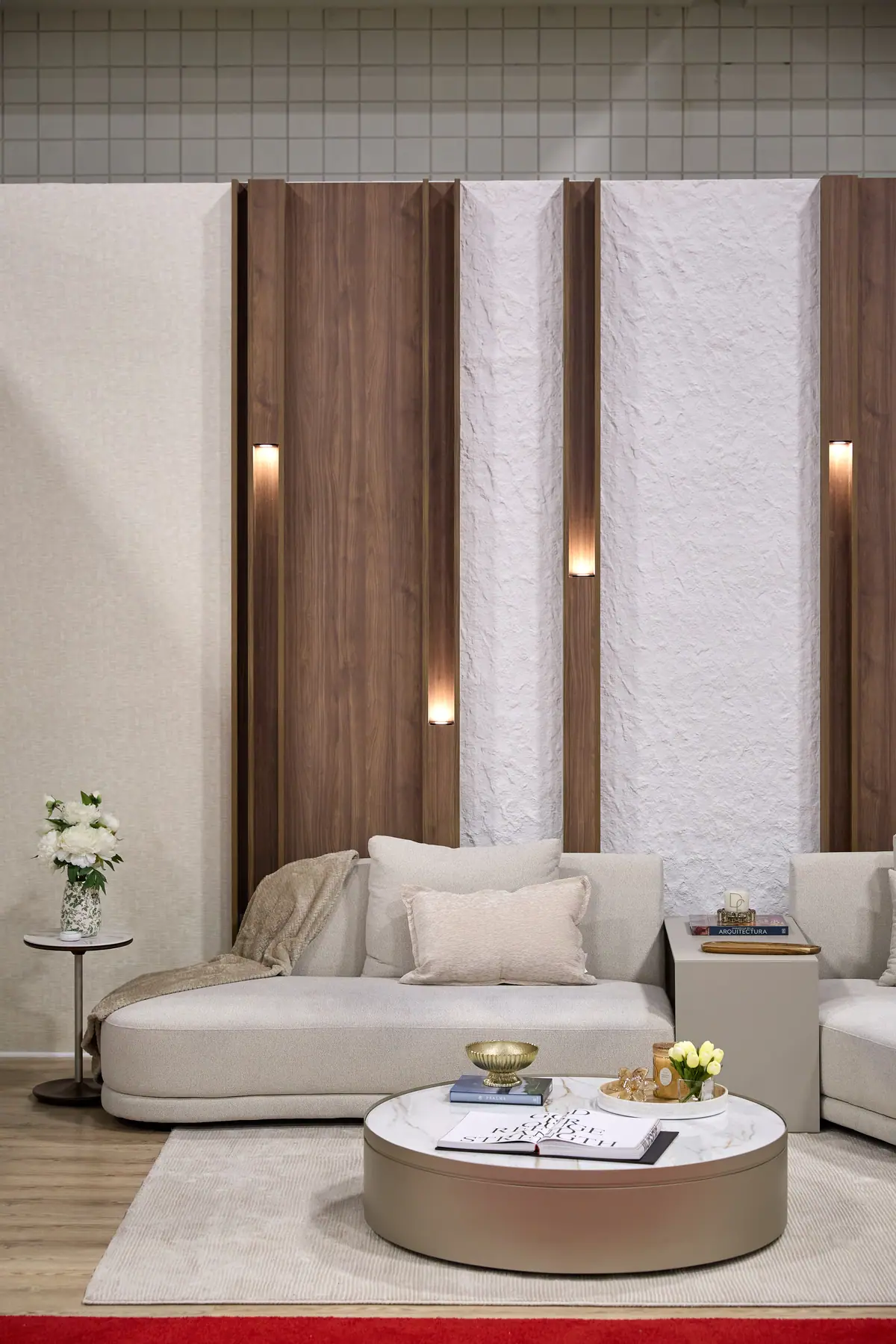 Luxury living room display with walnut slat wall, sconces, and round leather coffee table