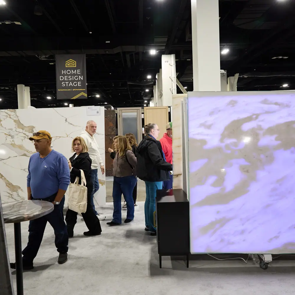 Attendees walking past a Home Design Stage banner and large stone slab display at the home show