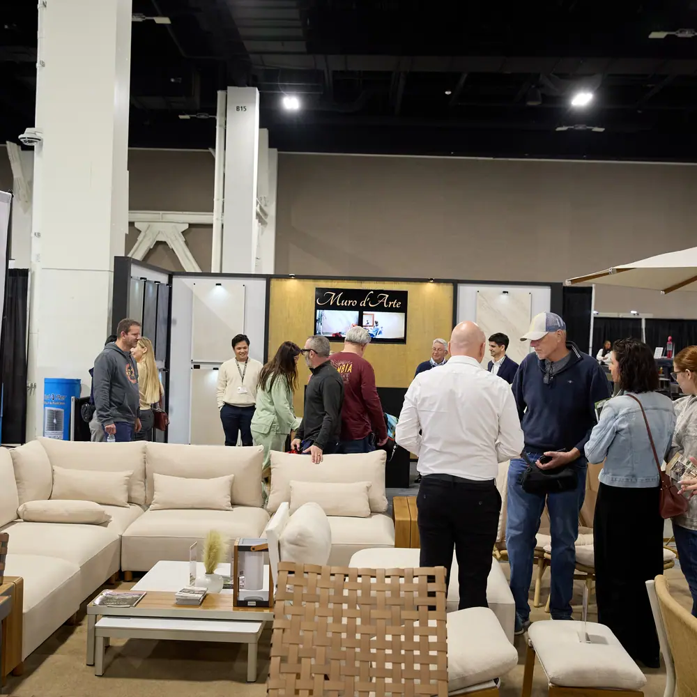 Attendees browsing outdoor furniture at a home show with Muro d'Arte stone booth in the background