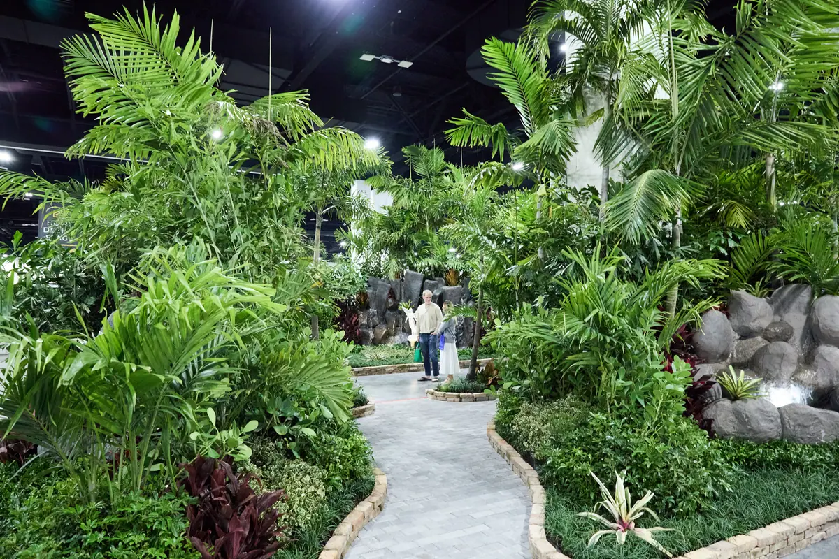 Winding garden path through lush tropical plants and a rock waterfall feature inside the home show