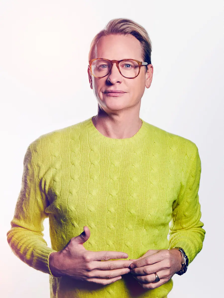 Carson Kressley portrait in a bright yellow cable-knit sweater and tortoiseshell glasses