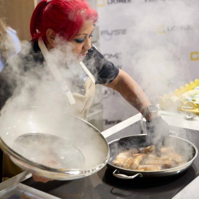 Chef with red hair sears fish in a steaming pan at a live culinary demonstration