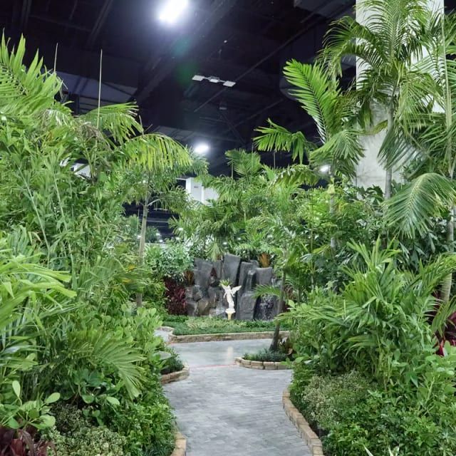 Winding stone path through a lush indoor tropical garden with a rock waterfall at a home show