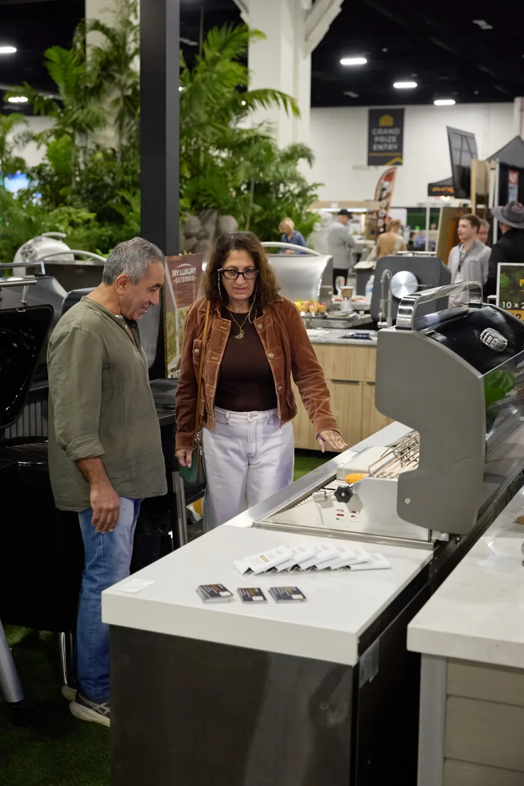 Couple examining an outdoor grill at the 2026 Fort Lauderdale Home Show exhibitor booth